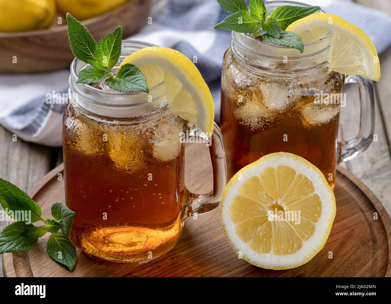 Zwei Gläser Eistee mit Zitronenscheibe und Minze auf einem Holztablett Stockfoto