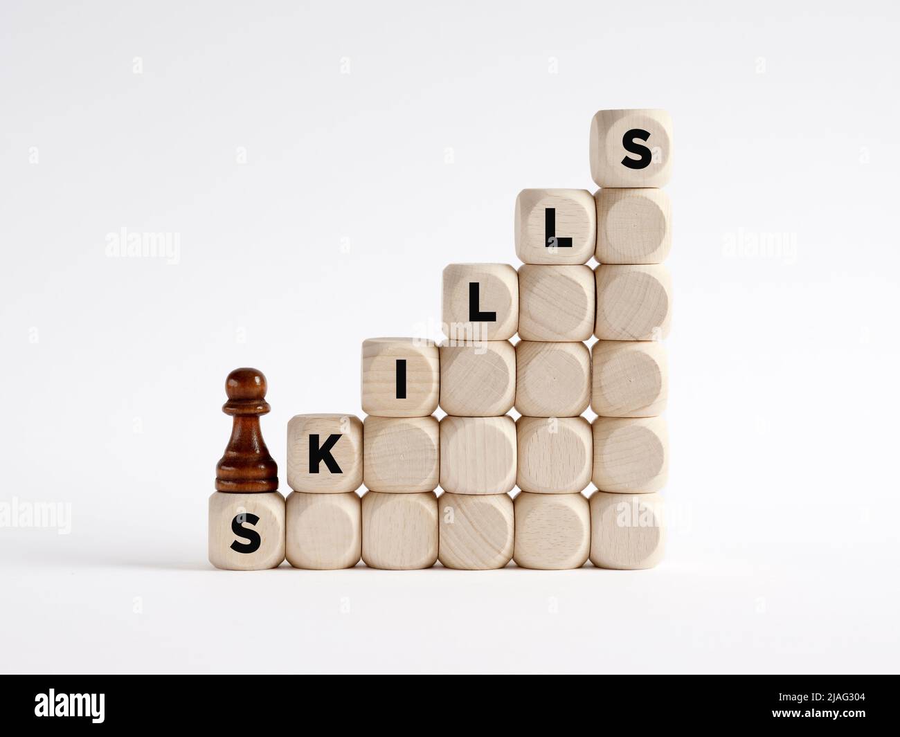 Entwicklung eines persönlichen, sozialen oder technischen Kompetenzkonzepts. Chess Pawn klettert die Leiter aus Holzwürfeln mit dem Wort Skills. Stockfoto