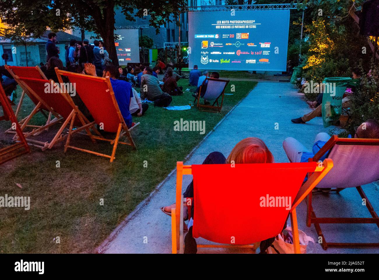 Paris, Frankreich, Publikum von hinten, Öffentliches Sitzen in Liegestühlen im Garten, Projektion, Nacht, 'Les Nuits Photographiques' Stockfoto