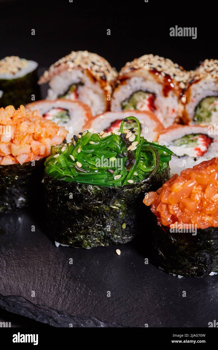 Nahaufnahme einer in Scheiben geschnittenen Sushi-Rolle mit Algen, Garnelen und mit Sesam bestreut. Stockfoto