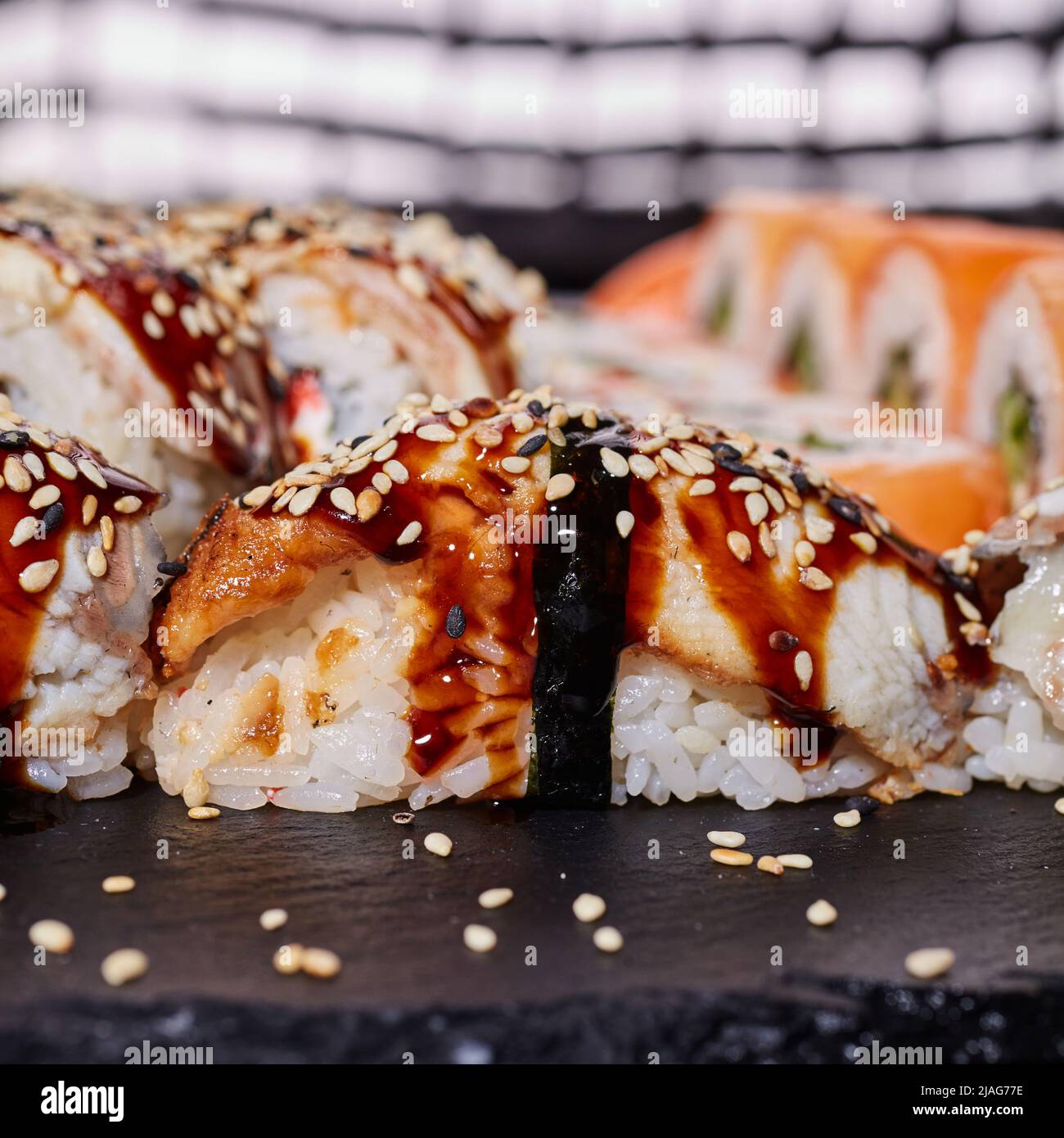 Nahaufnahme eines Nigiri-Sushi, das mit Sesamsamen bestreut und mit Sauce beträufelt ist. Stockfoto
