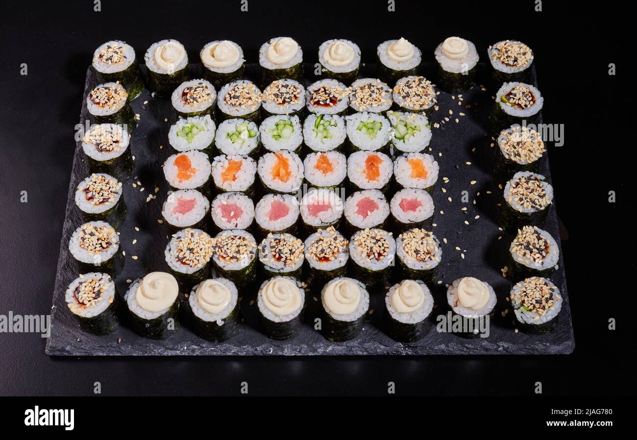 Japanisches Sushi-Set. Verschiedene Arten von Maki Rollen auf einem Teller auf einem Steingrund. Stockfoto