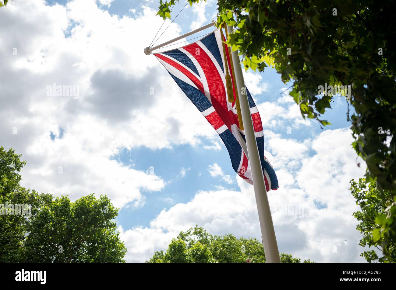 Union Jack fliegt im Wind auf der Stange zwischen Bäumen Stockfoto