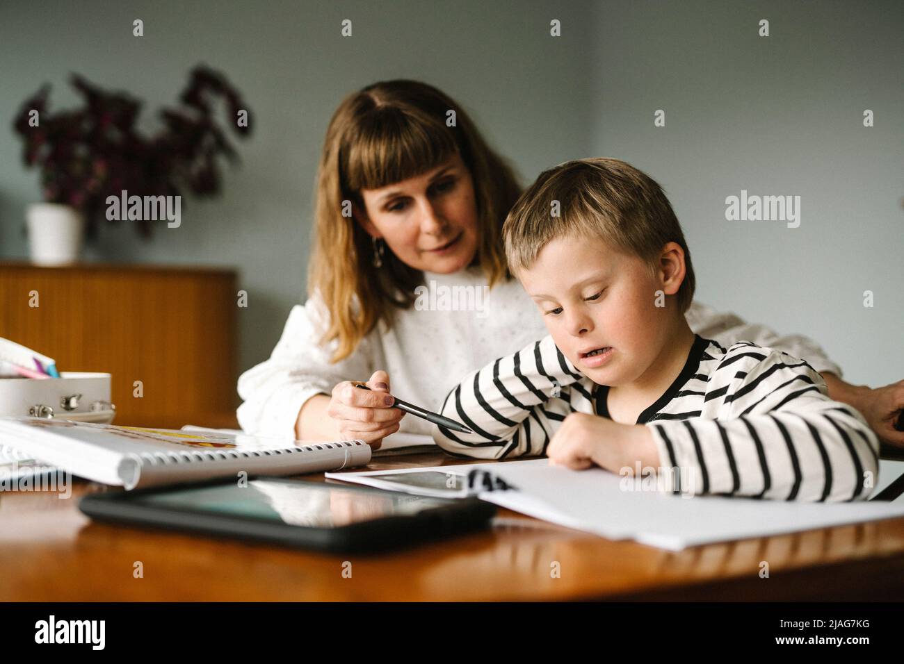 Mutter unterrichtet Sohn mit Behinderung während der Heimschoolung zu Hause Stockfoto