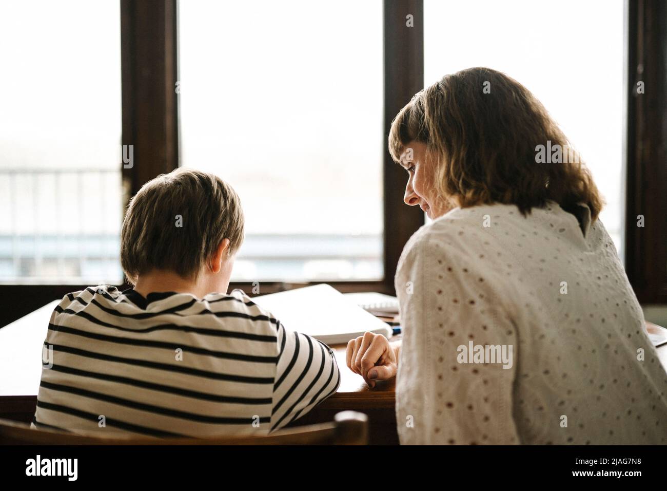 Rückansicht des Sohnes mit Behinderung, der von der Mutter zu Hause studiert Stockfoto