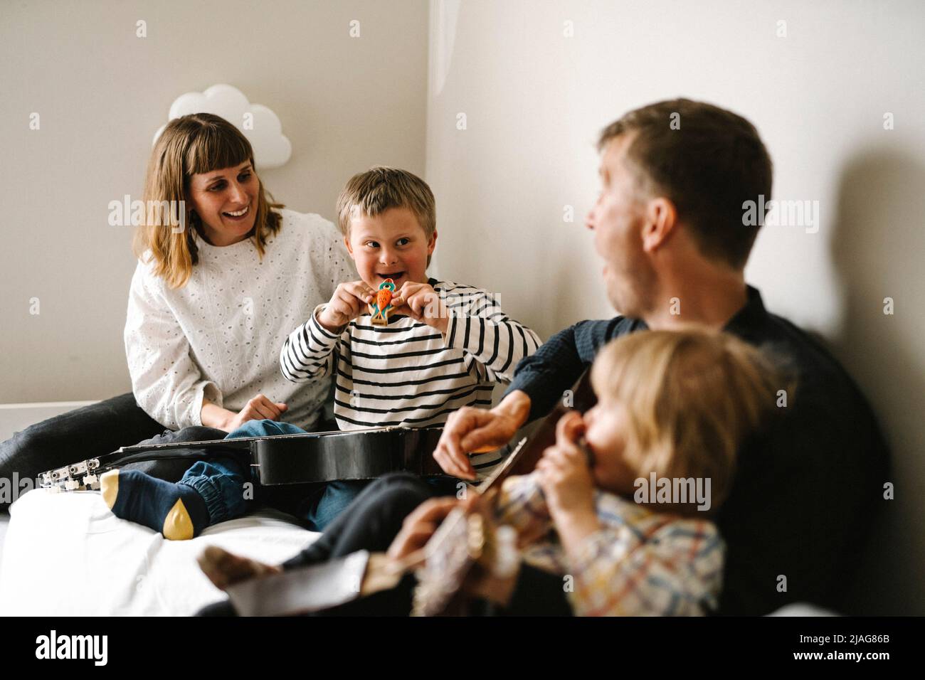 Eltern im Gespräch mit Sohn mit Down-Syndrom sitzen im Schlafzimmer zu Hause Stockfoto