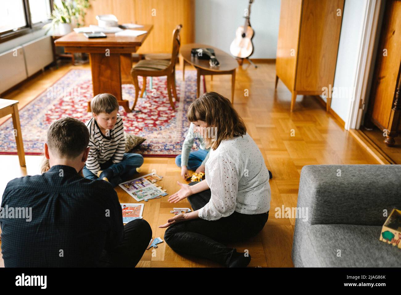 Eltern fügen Puzzleteile mit Kindern im Wohnzimmer zusammen Stockfoto