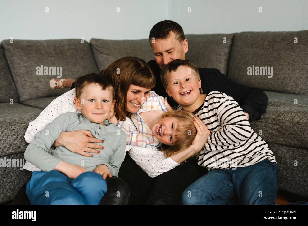 Porträt glücklicher Kinder mit Eltern gegen Sofa im Wohnzimmer Stockfoto