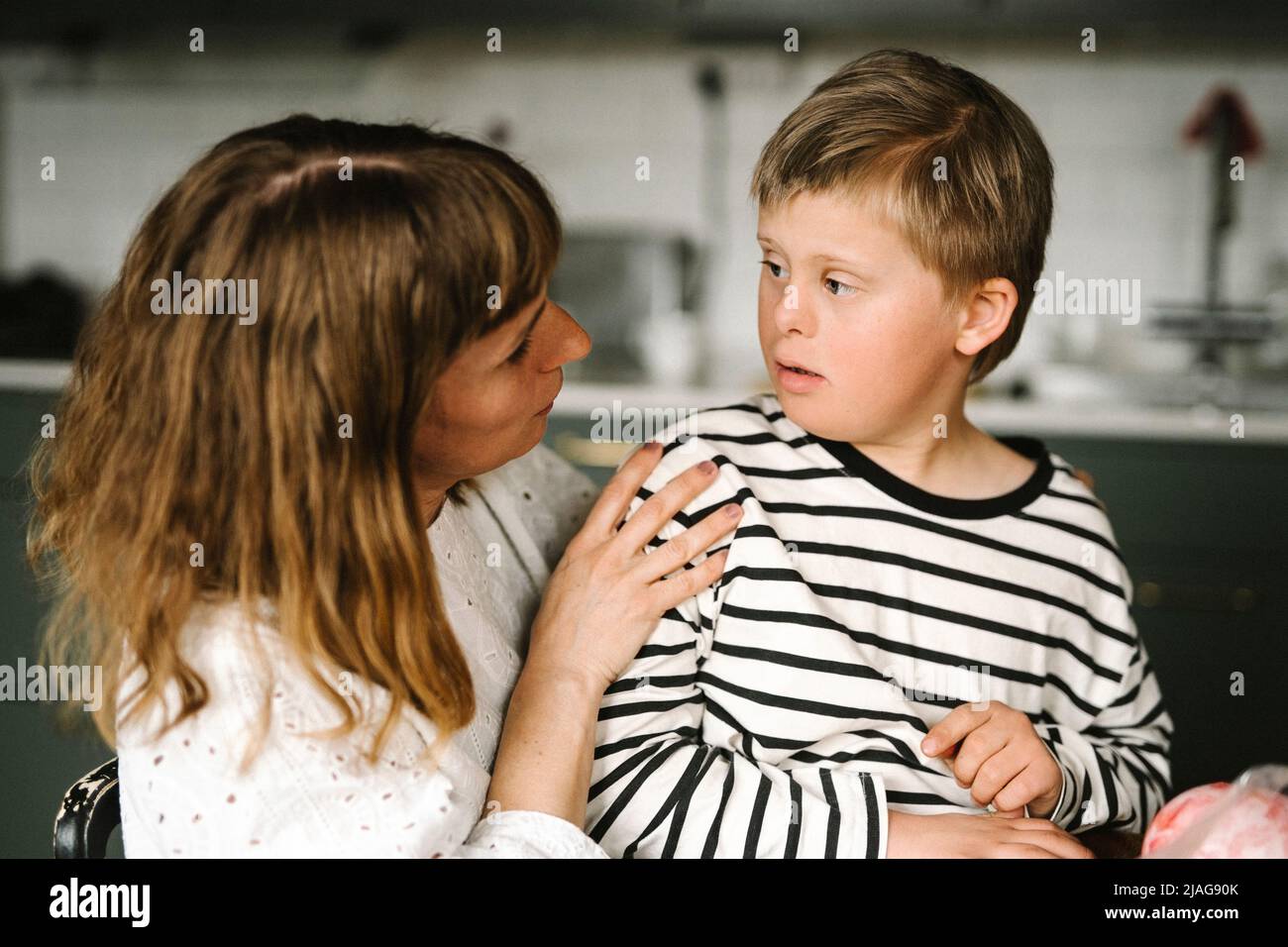Mutter im Gespräch mit Sohn, der zu Hause ein Down-Syndrom hat Stockfoto