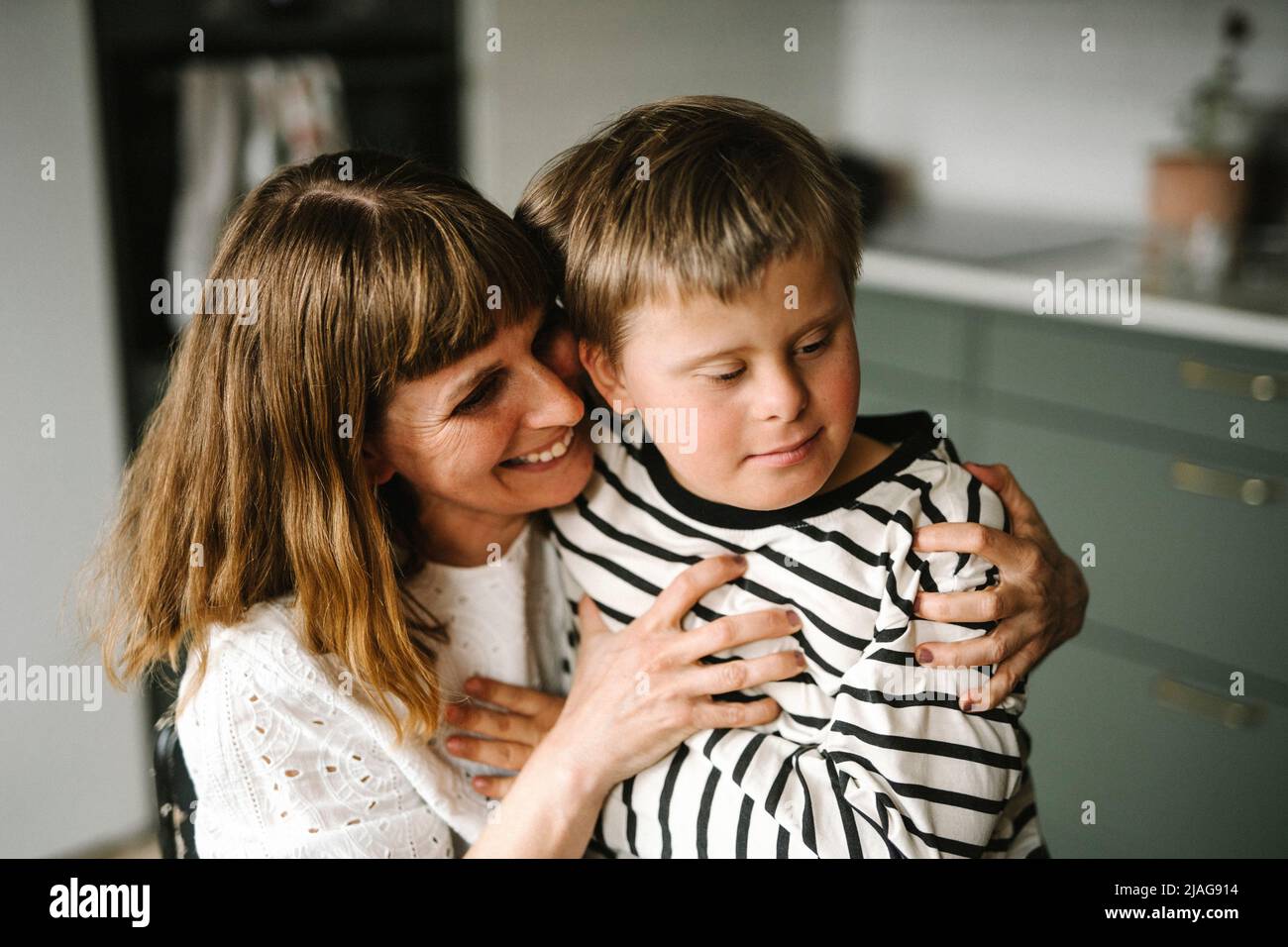Glückliche Mutter umarmt Sohn mit Behinderung zu Hause Stockfoto