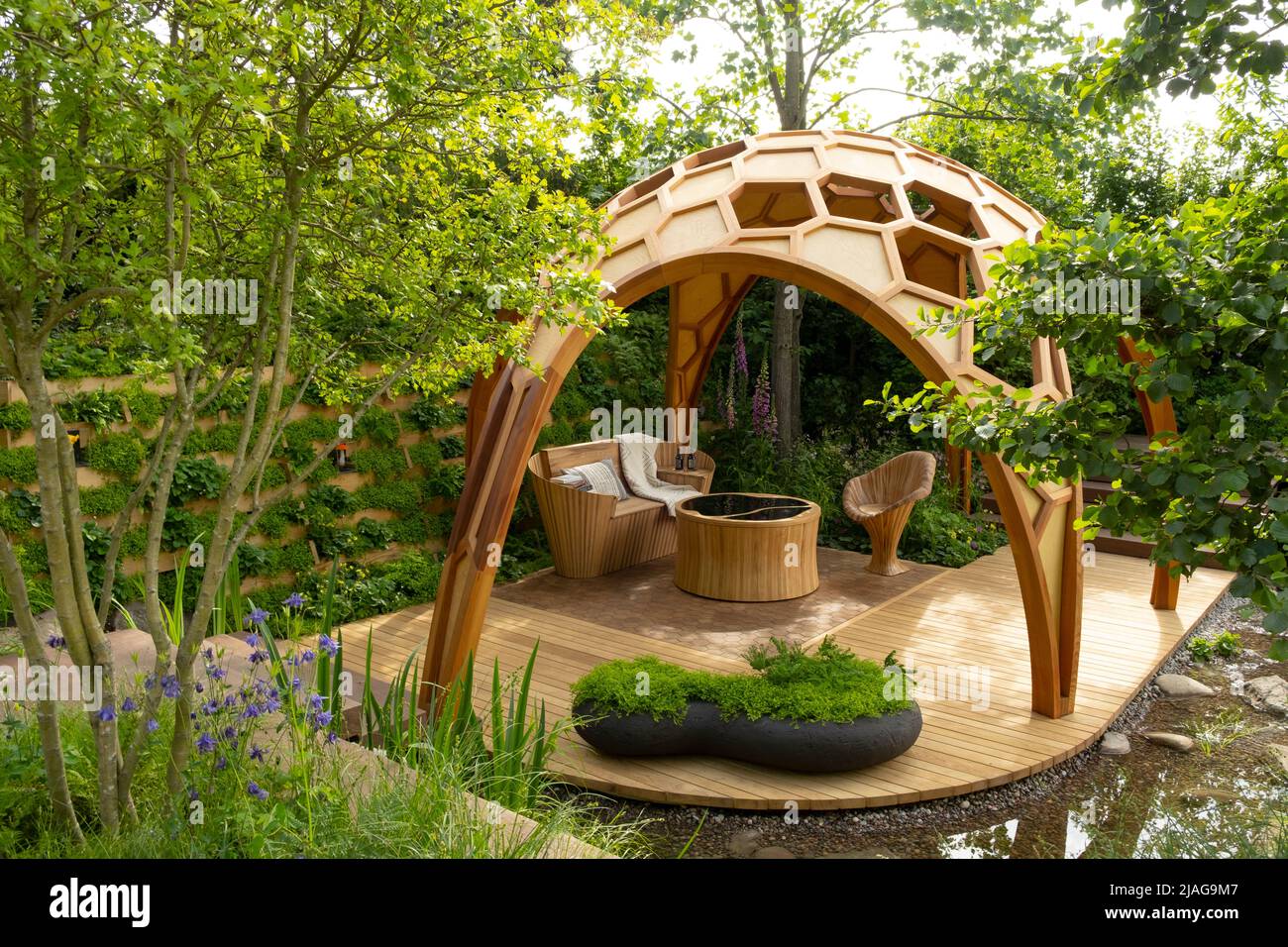 Ein kuppelförmiger Pavillon und ein tiefer bedeckter Sitzbereich in einem Waldgebiet im Meta Garden: Growing the Future, entworfen von Joe Perkins Stockfoto