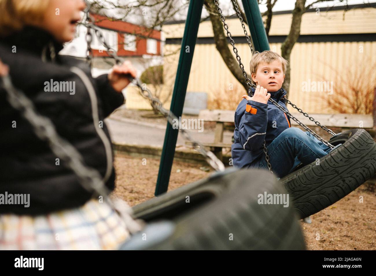 Schwester schwingt mit Bruder mit Behinderung im Park Stockfoto