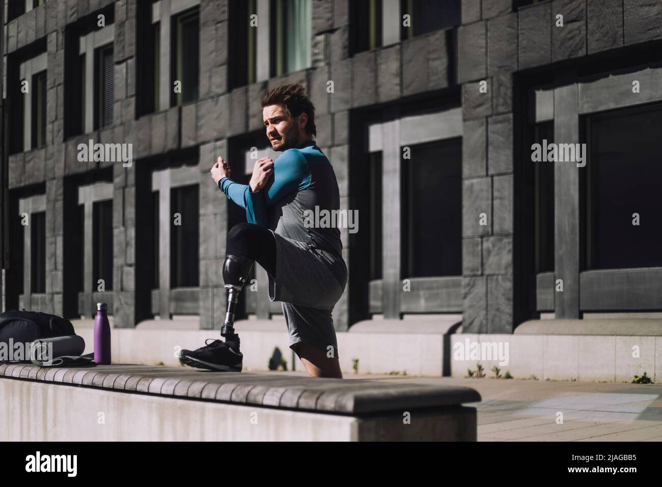 Junger Mann mit Behinderung macht an sonnigen Tagen Aufwärmübungen Stockfoto