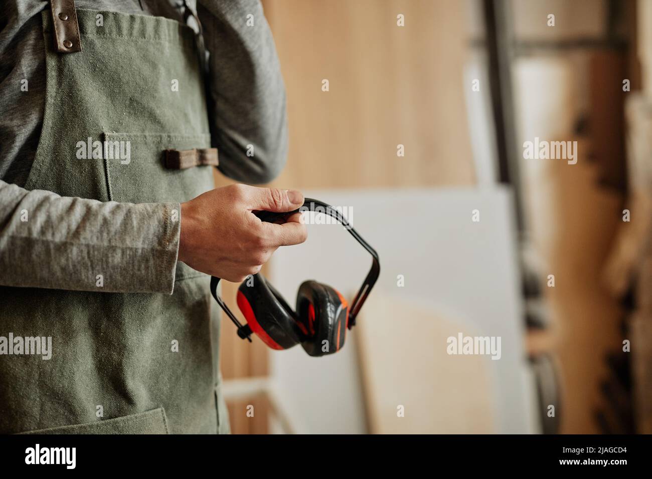 Nahaufnahme eines Mitarbeiters mit geräuschreduzierenden Kopfhörern in Werkstatt, Produktion und Sicherheit, Kopierbereich Stockfoto