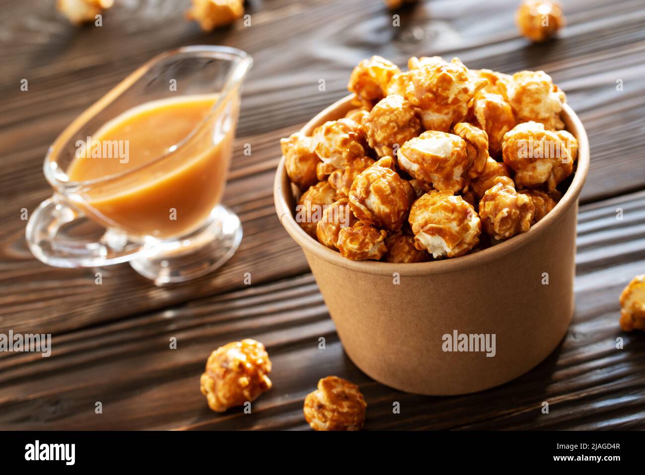 Karamellisiertes Popcorn in Papiereimer auf Holztisch Stockfoto