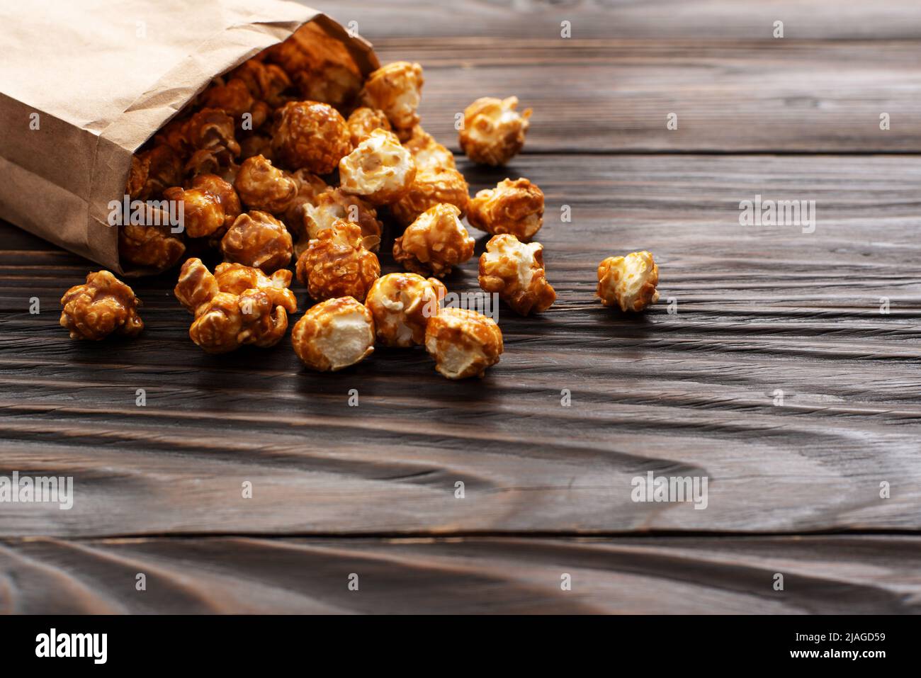 Karamellisiertes Popcorn in einer Papiertüte auf einem hölzernen Küchentisch Stockfoto