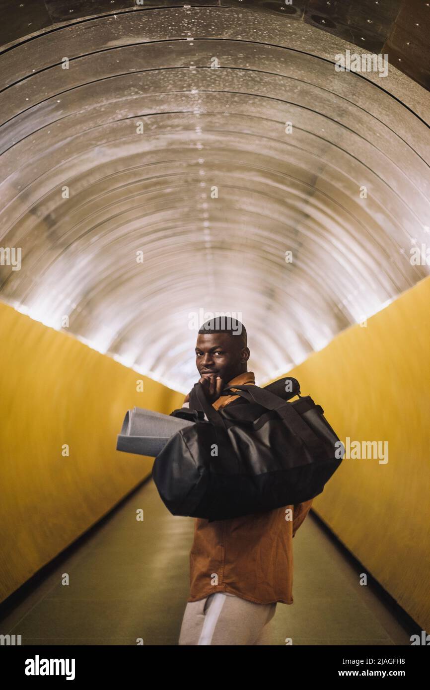 Porträt eines lächelnden jungen Mannes, der eine Tasche im Tunnel trägt Stockfoto