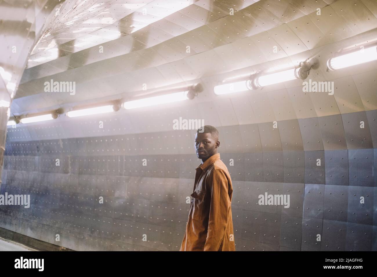 Junger Mann, der in einem beleuchteten Tunnel steht Stockfoto