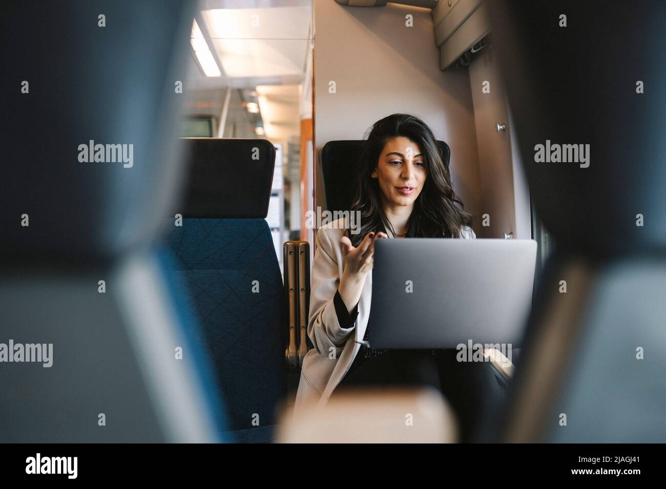 Geschäftsfrau, die im Zug sitzt, während sie über einen Laptop mit einem Videoanruf spricht Stockfoto