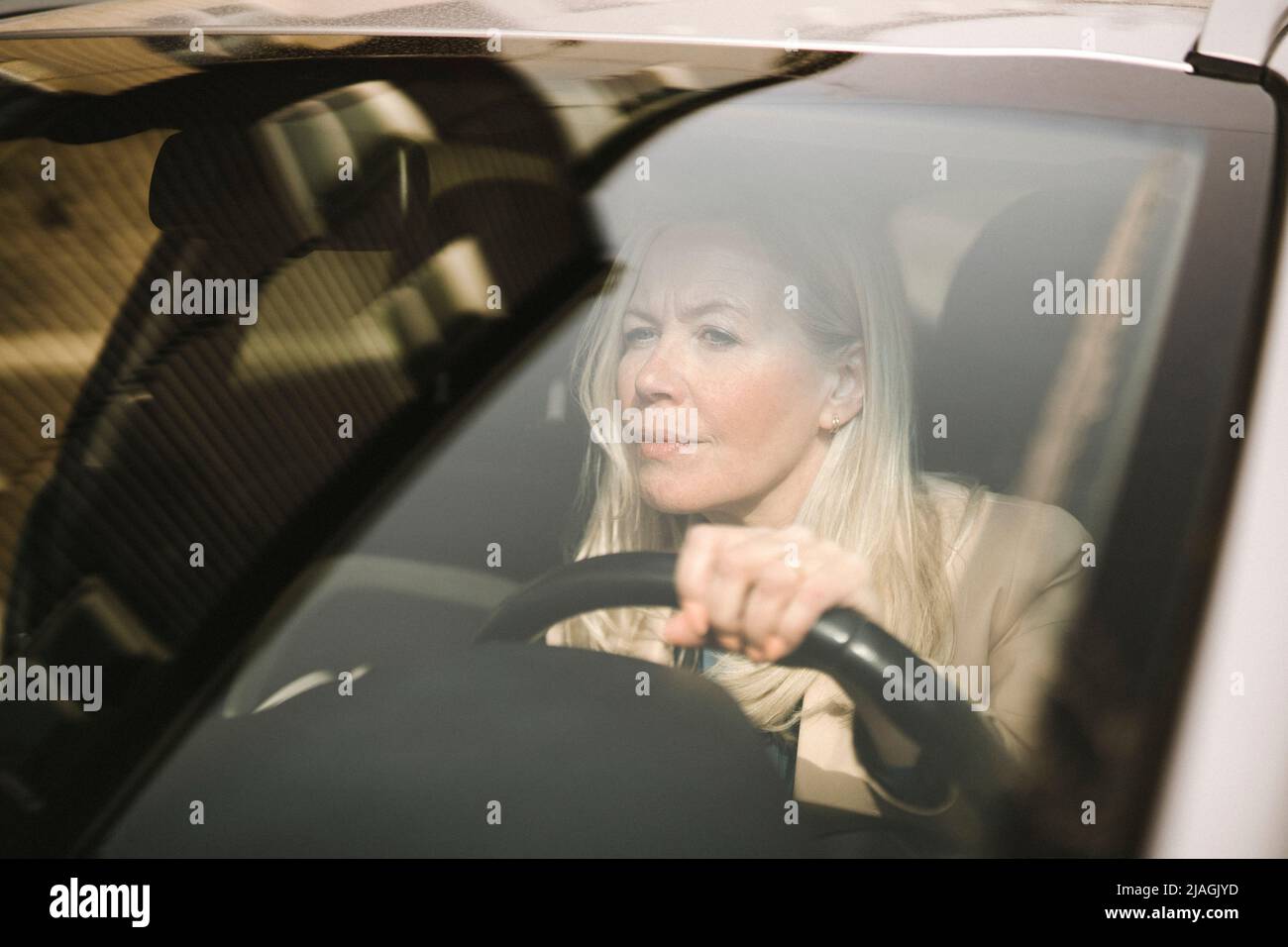 Neugierige Geschäftsfrau fährt Auto durch Windschutzscheibe gesehen Stockfoto