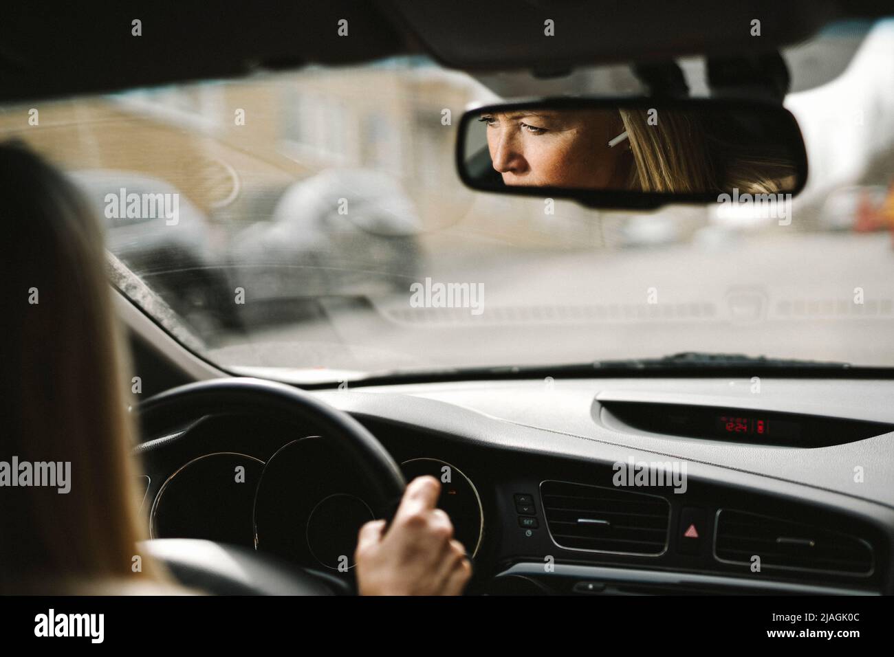 Spiegelung der Geschäftsfrau, die das Auto fährt, gesehen auf dem Rückspiegel Stockfoto