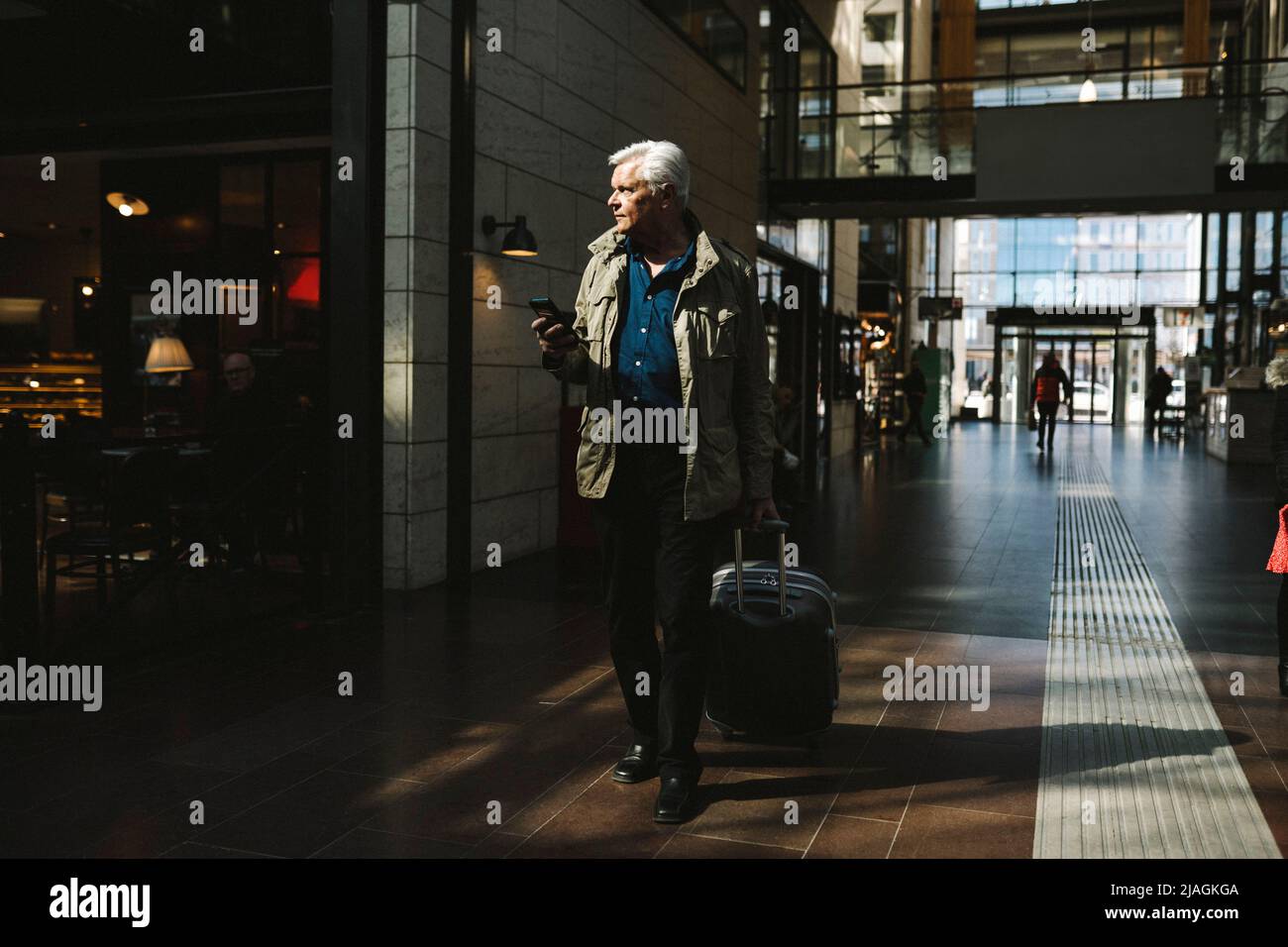 Geschäftsmann zieht am Bahnhof Gepäck mit Rädern Stockfoto