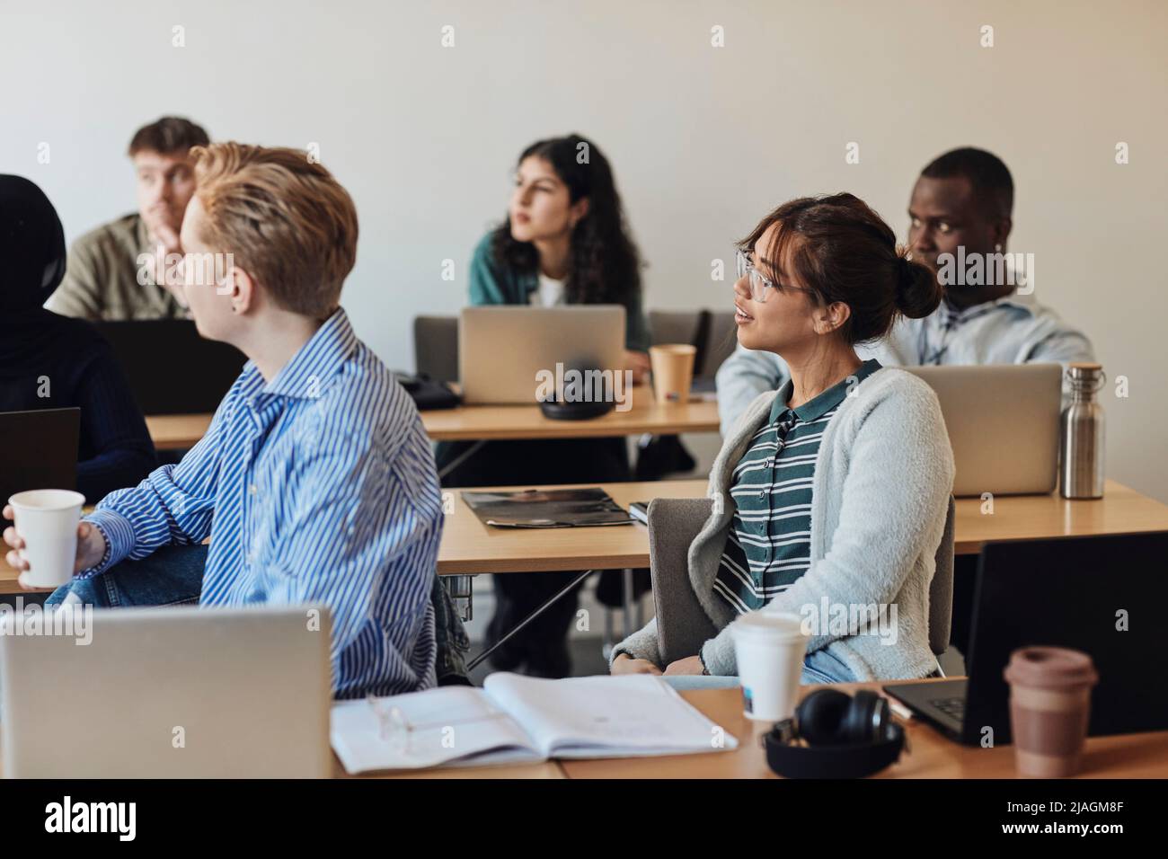Junge Studenten blicken weg, während sie die Vorlesung im Klassenzimmer besuchen Stockfoto