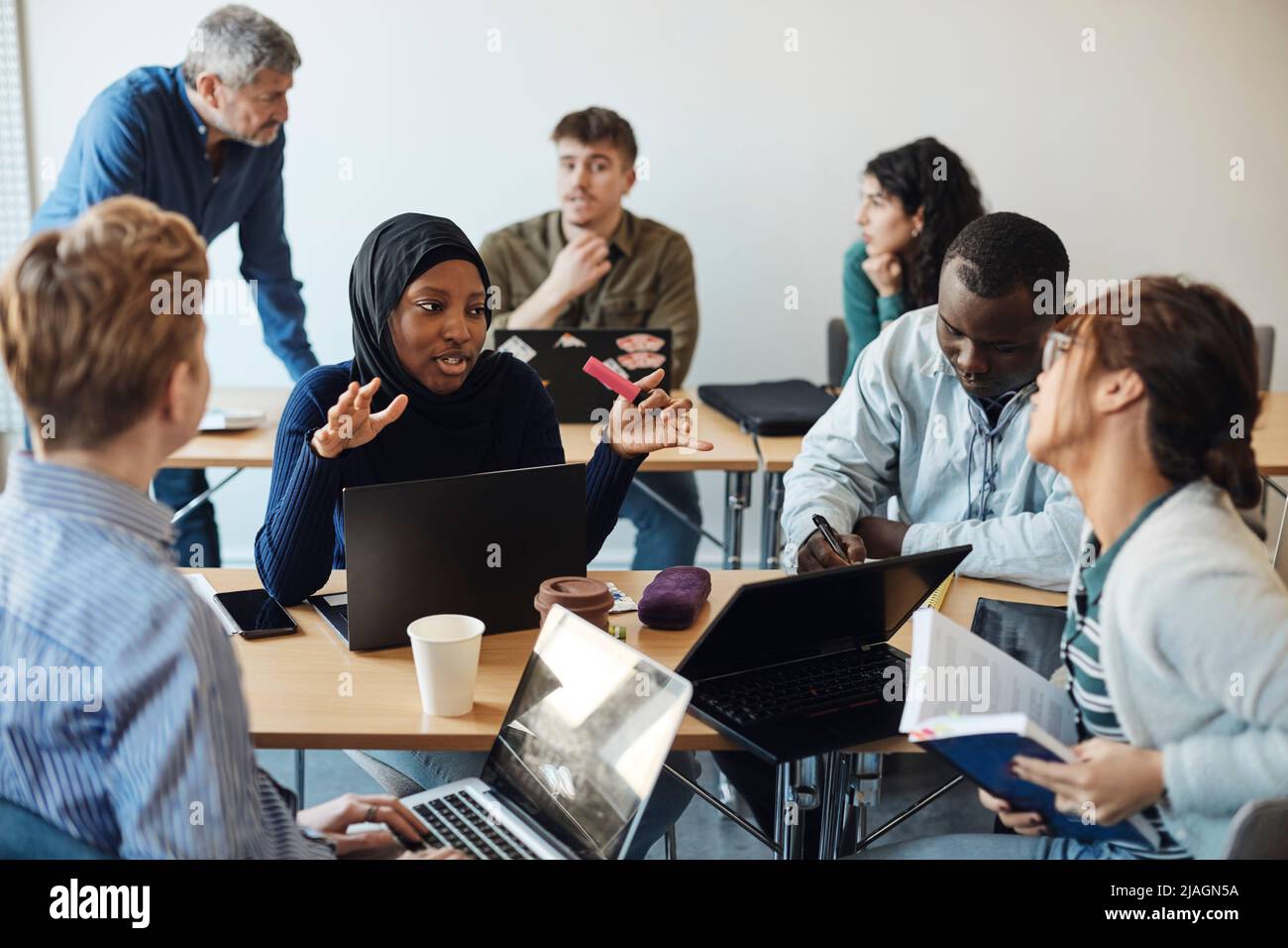 Multirassische Studenten diskutieren miteinander, während sie im Klassenzimmer sitzen Stockfoto