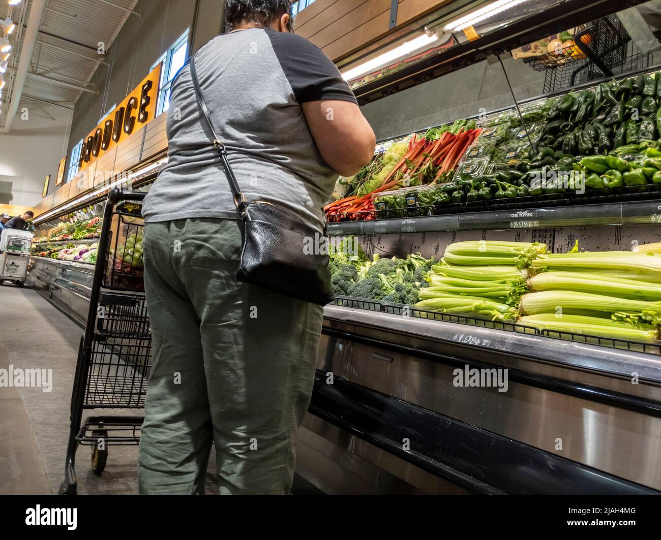 Mill Creek, WA USA - ca. Mai 2022: Abgewinkelte Ansicht einer übergewichtigen Frau, die in einem Town and Country Lebensmittelgeschäft Gemüse kauft Stockfoto