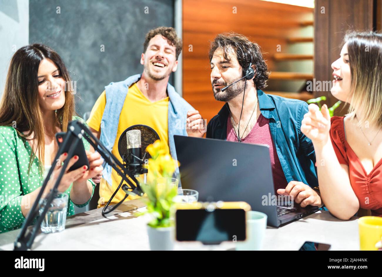 Junge glückliche Menschen teilen Podcast auf Streaming-Plattform mit Mikro-Telefonkamera - modernes Lifestyle-Konzept mit smarten Millennial-Männer und Frauen Stockfoto