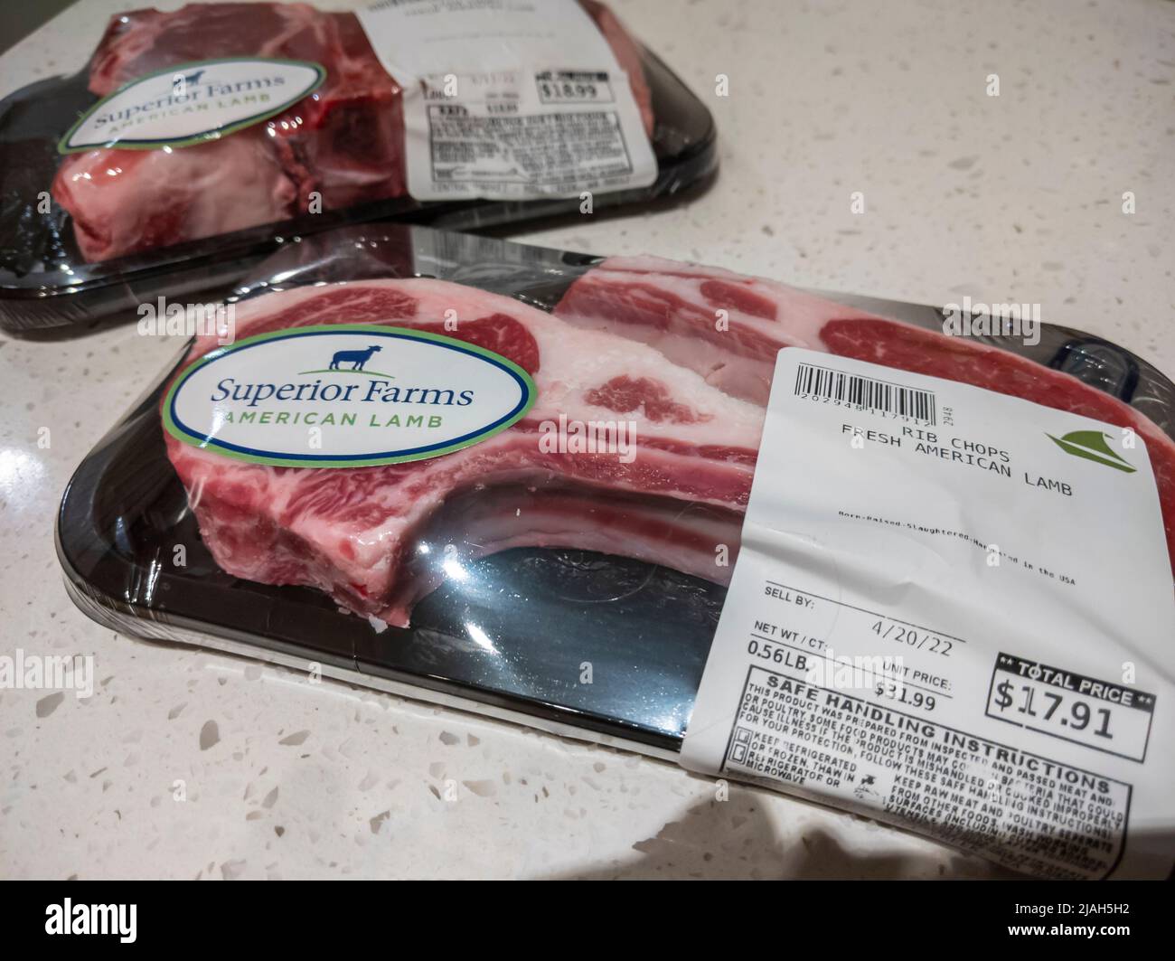 Seattle, WA, USA - ca. April 2022: Angewinkelter, selektiver Fokus auf zwei Päckchen mit frischem amerikanischem Lamm auf einer Küchentheke. Stockfoto