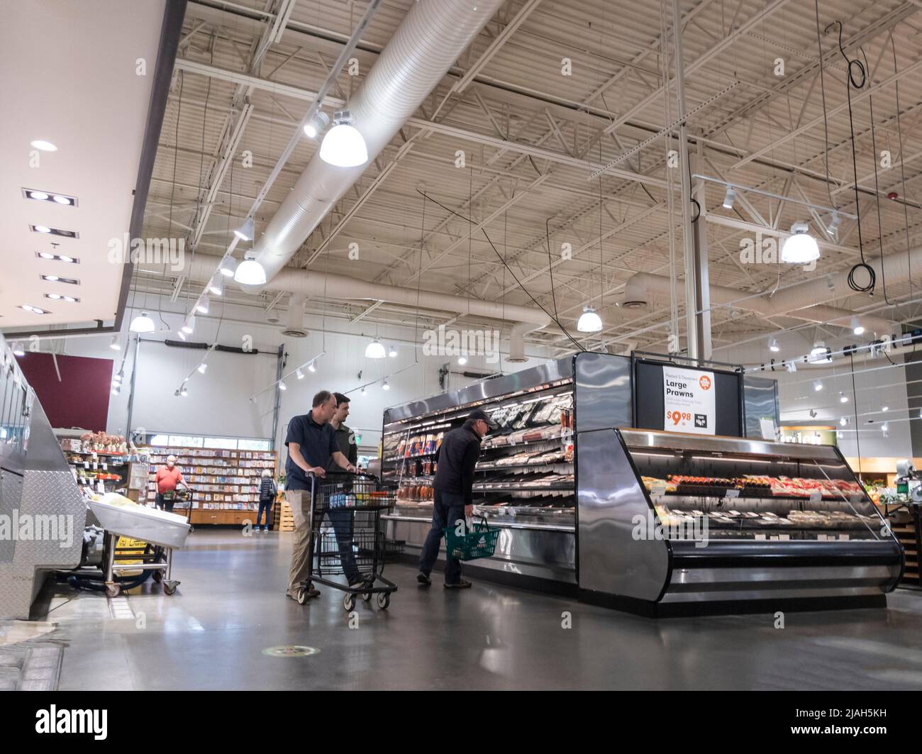 Mill Creek, WA USA - ca. Mai 2022: Abgewinkelte Ansicht zweier Männer, die in der Produktion- und Fleischabteilung eines Stadt- und Landmarktes zusammen einkaufen. Stockfoto