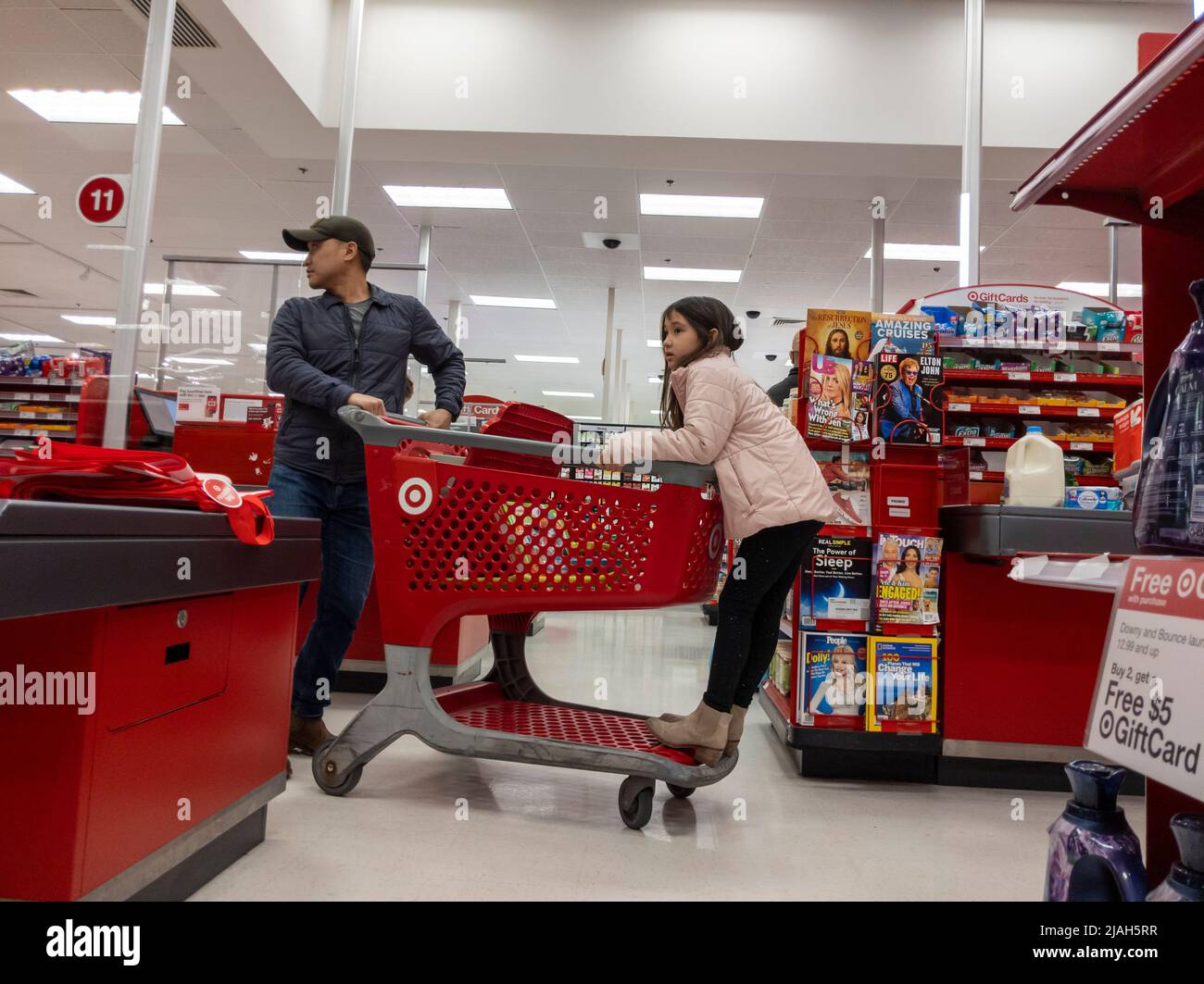 Lynnwood, WA USA - ca. März 2022: Ansicht eines Vaters und einer Tochter, die einen Einkaufswagen in einem Target Store zum Kassenschalter schieben. Stockfoto