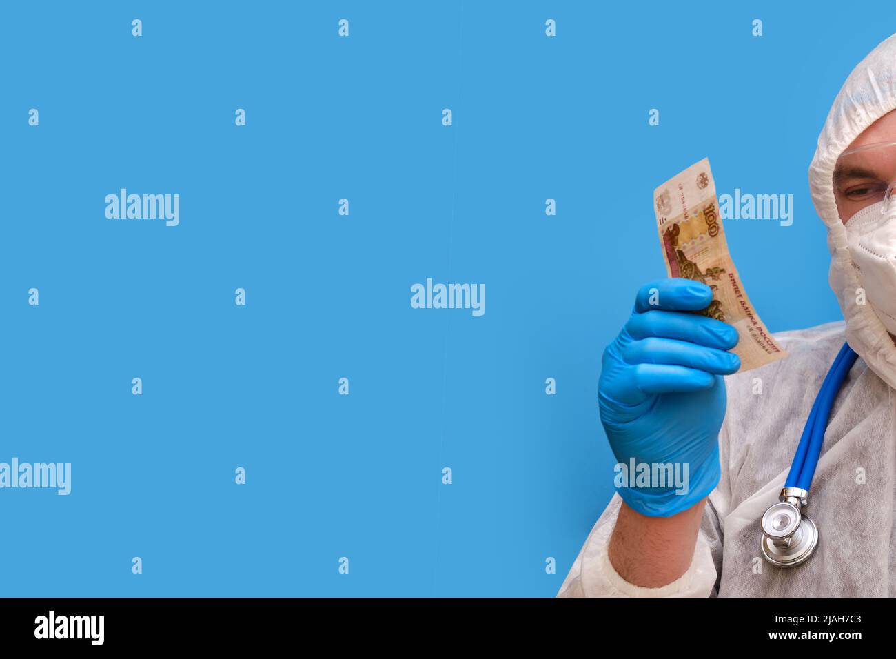 Arzt in Schutzanzug-Uniform mit Schutzbrille und medizinischer Gesichtsmaske auf einem Studio-blauen Hintergrund, Kopierraum Stockfoto