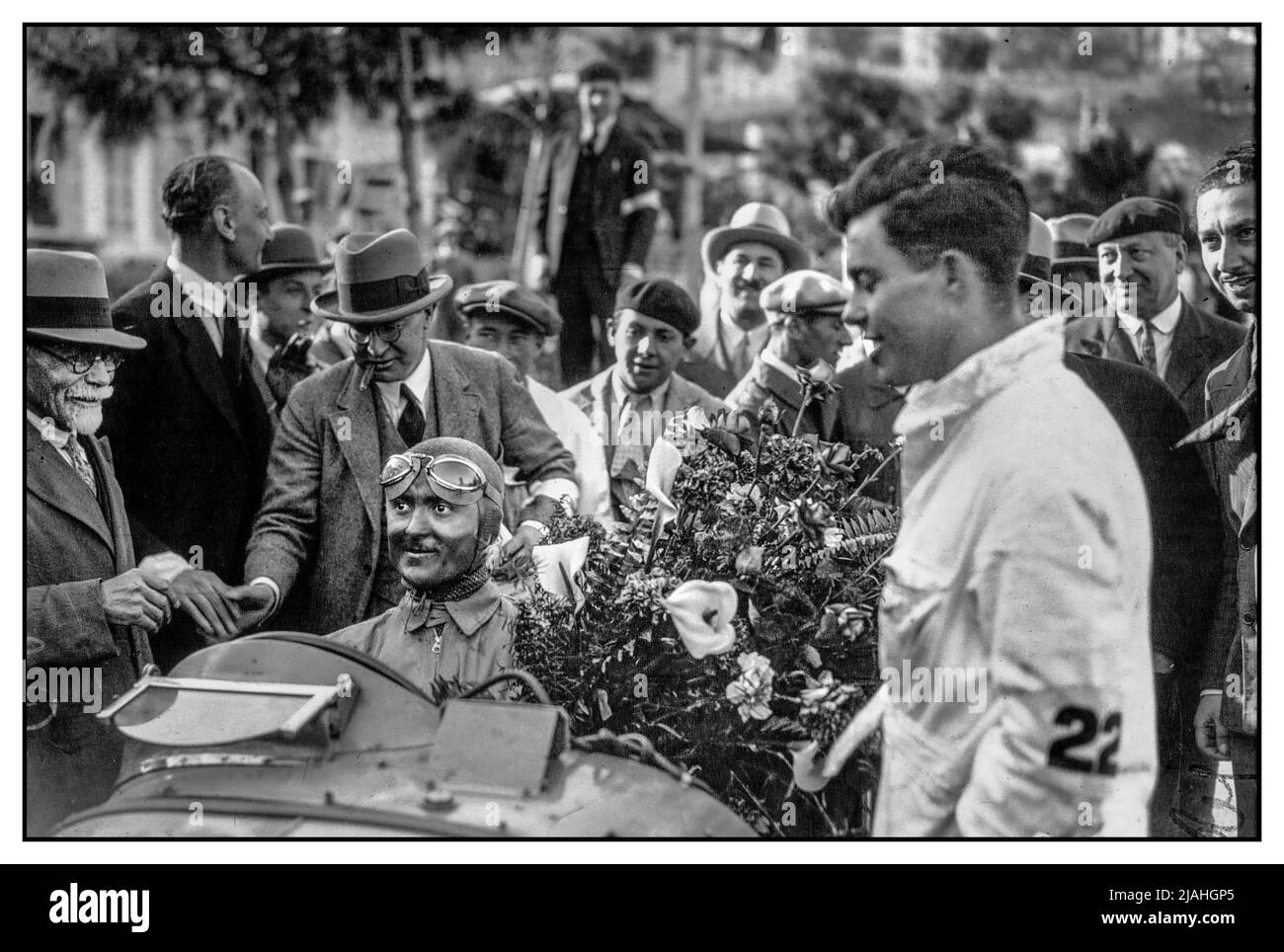 MONACO GRAND PRIX 1931 Louis Chiron fährt mit einem Bubugtartigen, mit Öl bedeckten Sieger des Grand Prix von Monaco 1931, sein Eintrag #22 hat gewonnen. Der Mechaniker von Burgenia Lucien Wurmser (rechts, in weißer Kleidung mit #22 am Arm.) MONACO GRAND PRIX SIEGER 1931 Louis Chiron mit den Siegerblumen Stockfoto