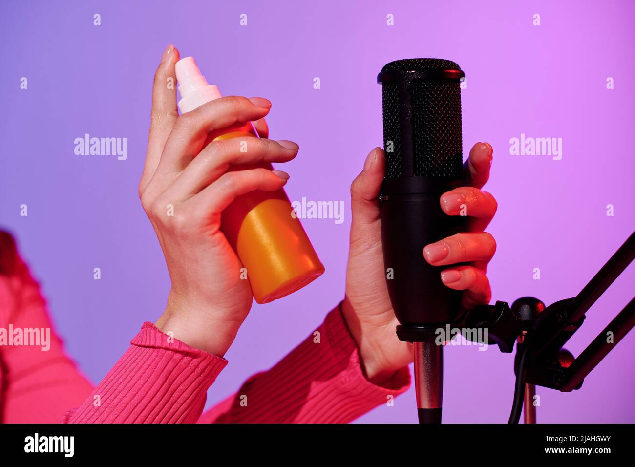 Nahaufnahme einer nicht erkennbaren Frau, die eine Flasche parfümierten Körpernebels in der Hand hält und dabei Geräusche für ASMR aufzeichnet Stockfoto