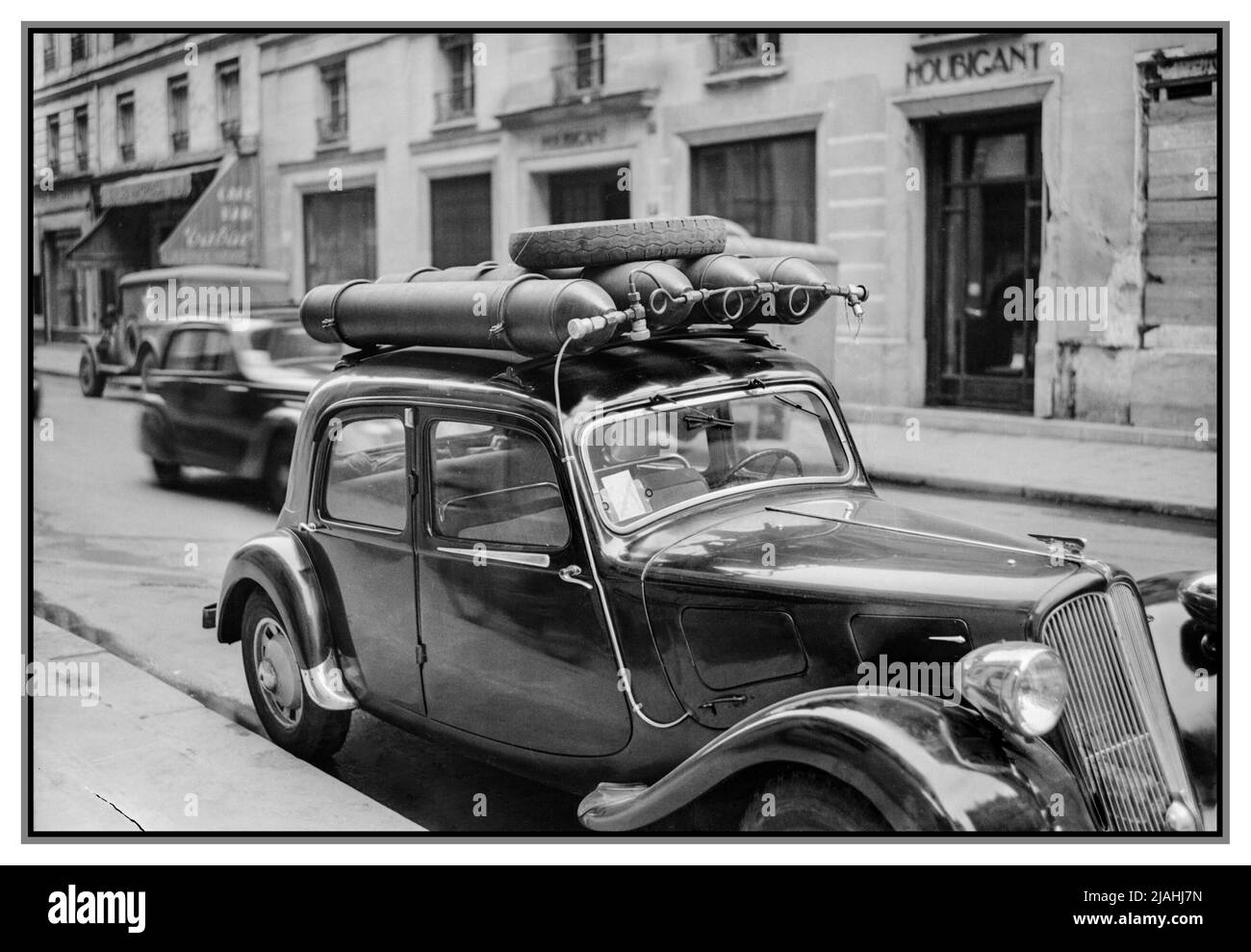 Alternative zur Treibstoffflasche nach dem Krieg WW2. Rationierung von Frankreich Pariser Verkehr, Frühjahr 1945- Alltag in der Nachkriegszeit Paris, Frankreich, 1945 Blick auf eine Pariser Straße, zeigt ein Auto, das umgebaut wurde, um mit Gas zu fahren, anstatt mit Benzin, das streng rationiert ist. Am Dach des Fahrzeugs sind vier Gasflaschen befestigt, und ein kleiner Schlauch läuft seitlich am Fahrzeug und unter der Motorhaube ab. Datum 1945 Stockfoto