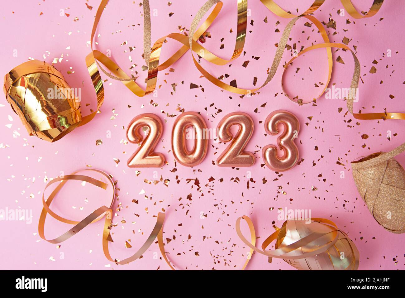 Draufsicht auf Roségold Zahlen 2023 mit Goldkonfetti und Glitzer auf rosa Hintergrund.Festliches Banner, flach Lay-Stil. Stockfoto