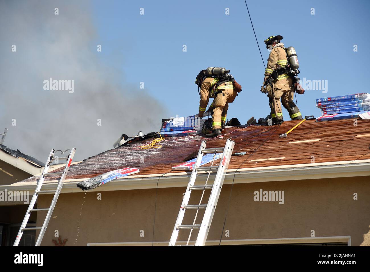 SDFD Feuerwehrleute, die auf dem Dach arbeiten, um bei einem Strukturbrand zu den verbleibenden Flammen zu gelangen Stockfoto
