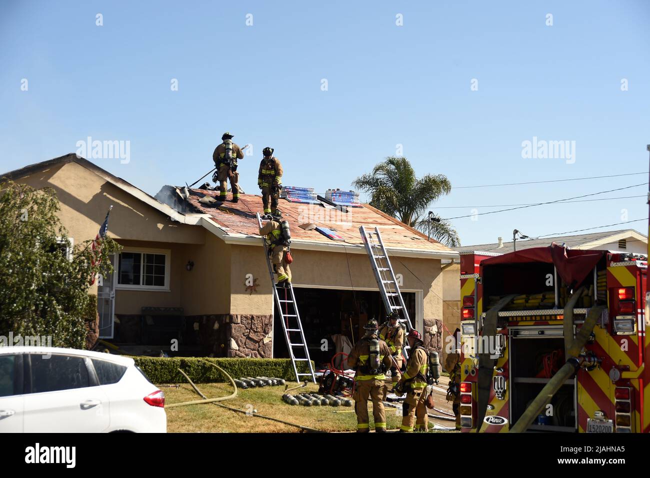 SDFD Feuerwehrleute, die auf dem Dach arbeiten, um bei einem Strukturbrand zu den verbleibenden Flammen zu gelangen Stockfoto