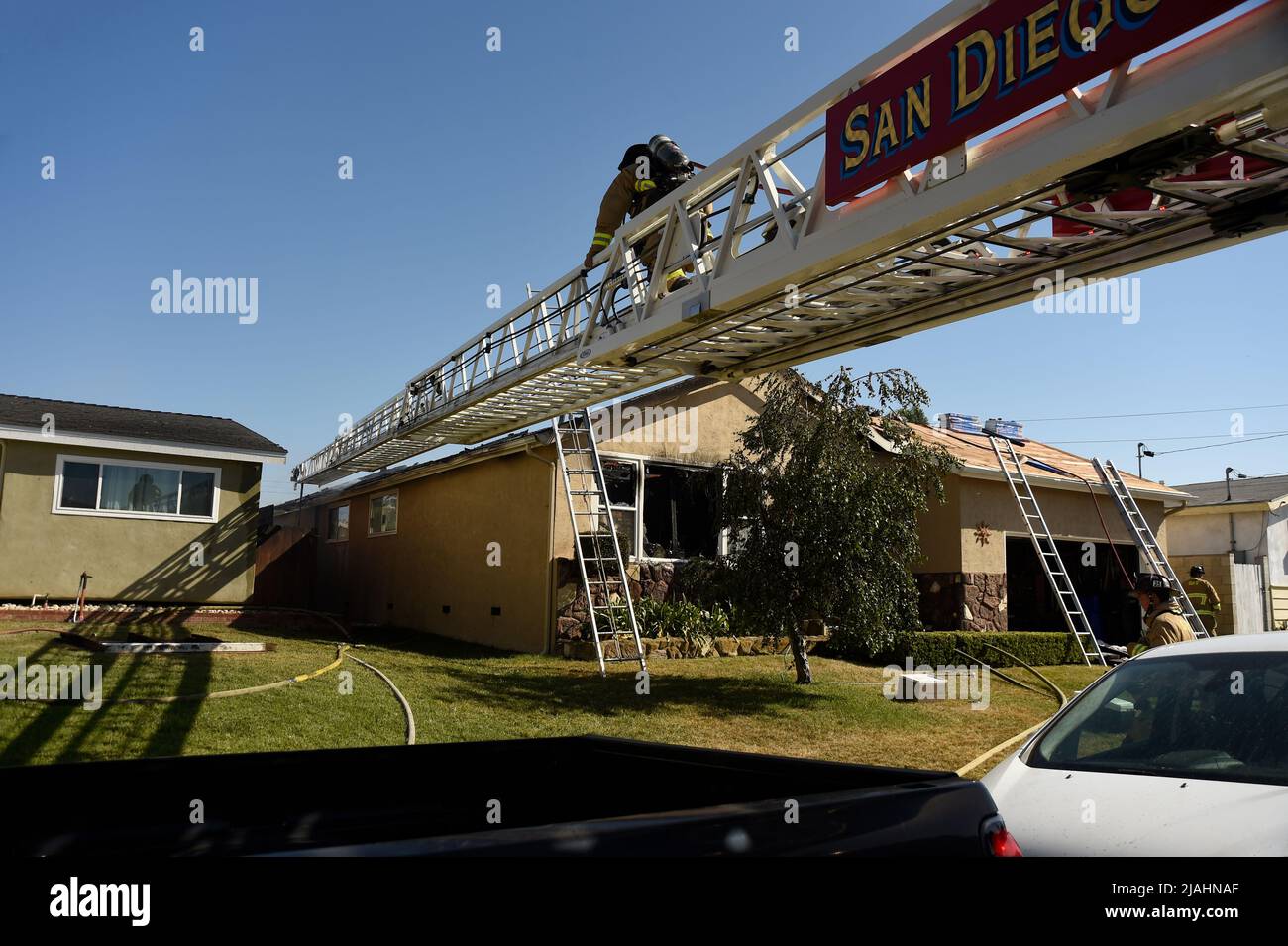 Der Feuerwehrmann bewegt sich die Leiter hoch, um Zugang zum Inneren der Struktur zu erhalten Stockfoto