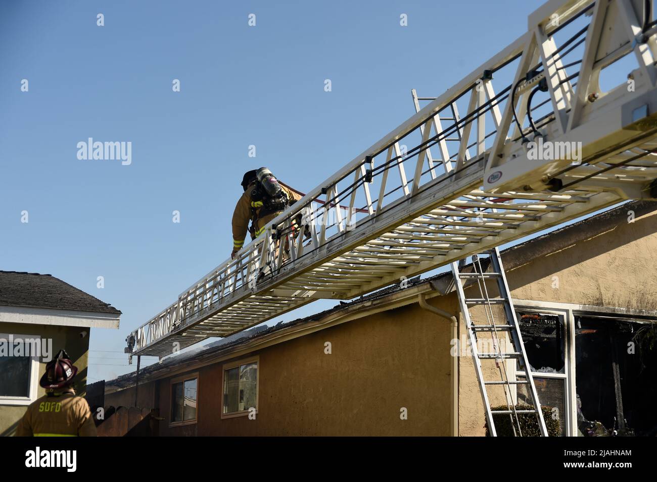 Der Feuerwehrmann bewegt sich die Leiter hoch, um Zugang zum Inneren der Struktur zu erhalten Stockfoto