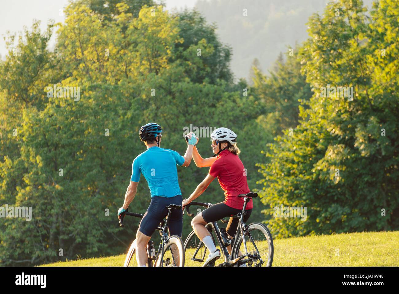 Straßenradler machen eine Radtour entlang einer landschaftlich reizvollen Radroute, genießen atemberaubende Sehenswürdigkeiten und geben High Five Stockfoto