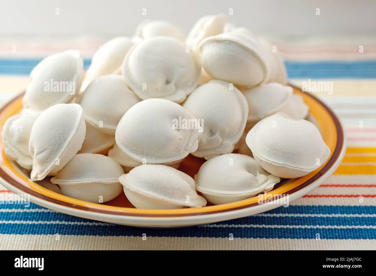 Rohe Knödel auf einem Teller. Gefrorene Knödel mit Fleisch. Halbfertigprodukte aus der Nahaufnahme von Teig und Fleisch. Stockfoto