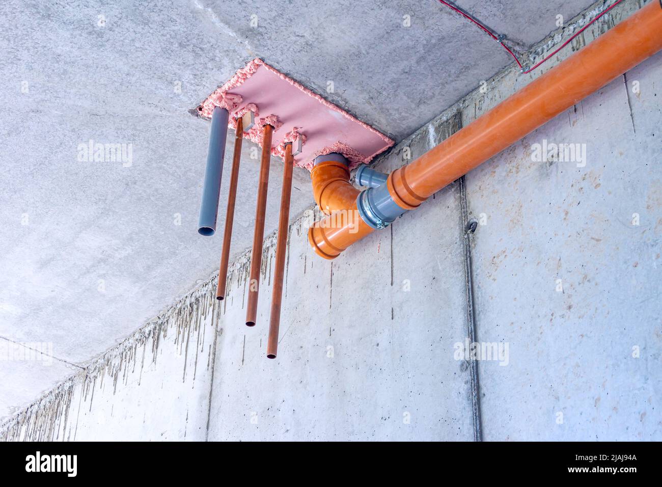 Installation von Wasser- und Abwasserleitungen in der technologischen Öffnung der Zwischenbodenüberlappung des Kellergeschosses, selektiver Fokus Stockfoto