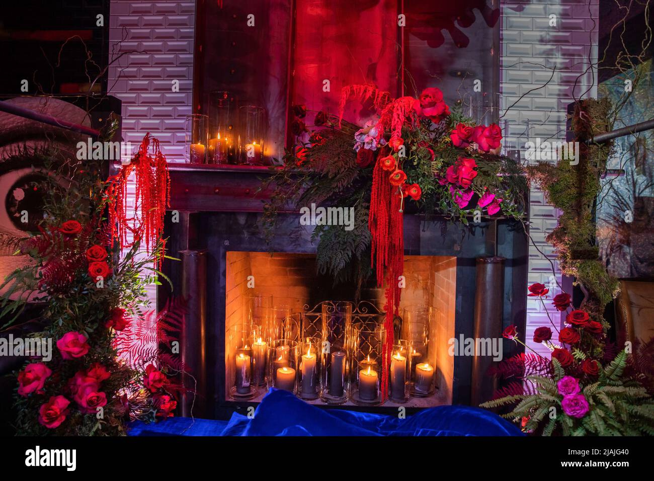 Helle Blumen in der Nähe des Kamins mit Kerzen. Stockfoto