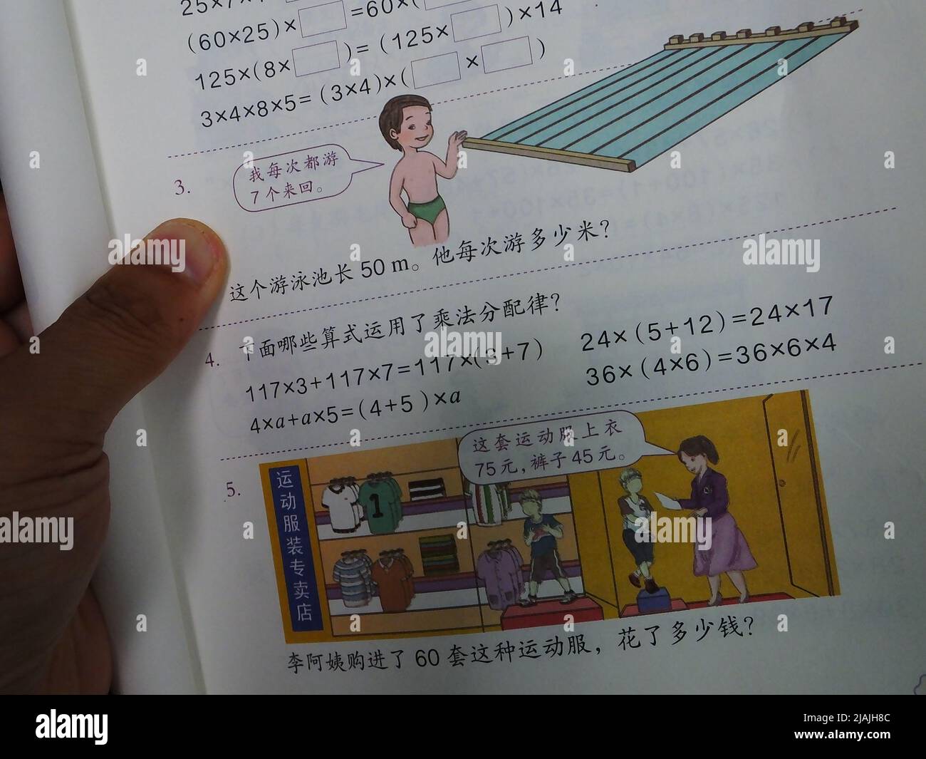 YICHANG, CHINA - 31. MAI 2022 - Ein Bürger zeigt die Illustrationen des zweiten Bandes des veröffentlichten Mathe-Lehrbuchs der vierten Klasse für Grundschulen Stockfoto