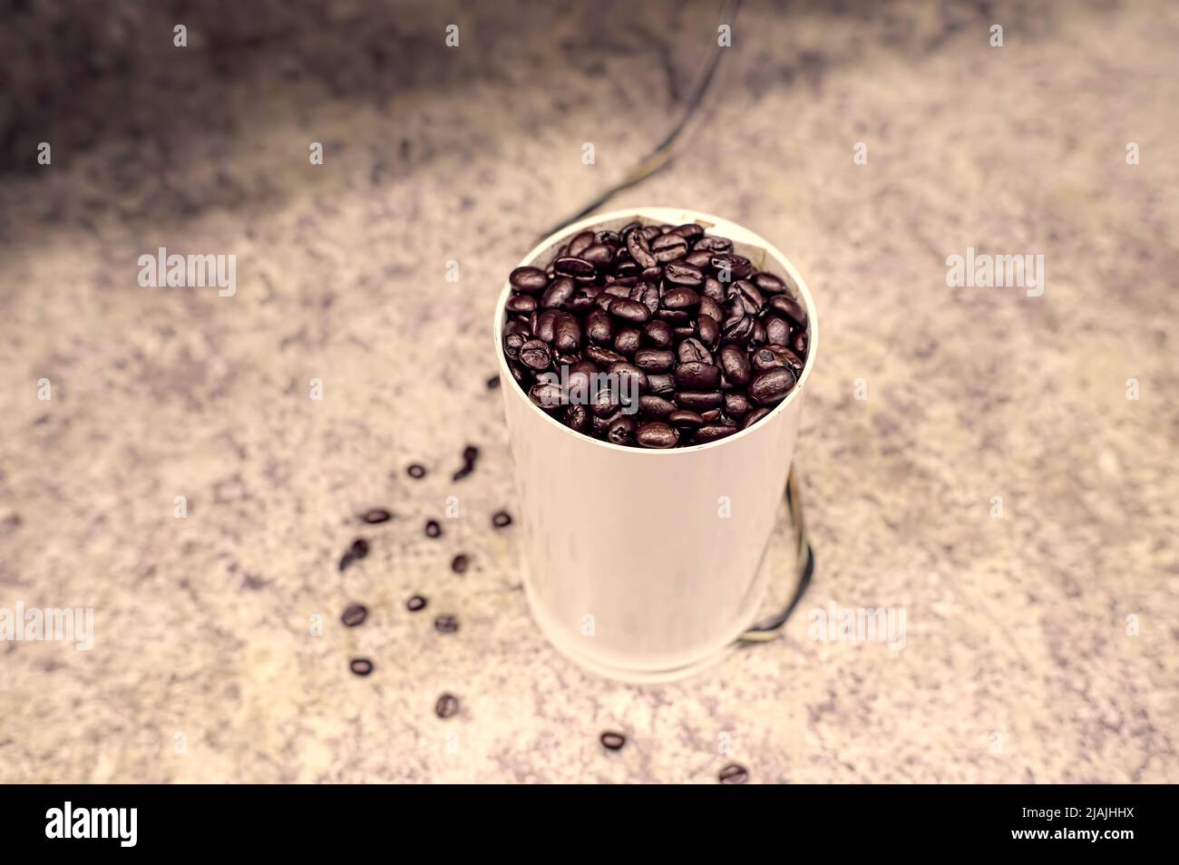 Ganze Kaffeebohnen in einer Mühle auf einer Küchenarbeitsfläche. Stockfoto