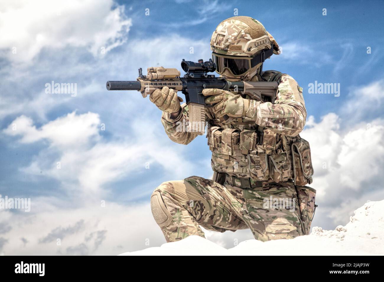 Voll ausgerüsteter Soldat, der auf einem Knie mit optischer Sicht auf das Dienstgewehr zielt. Stockfoto