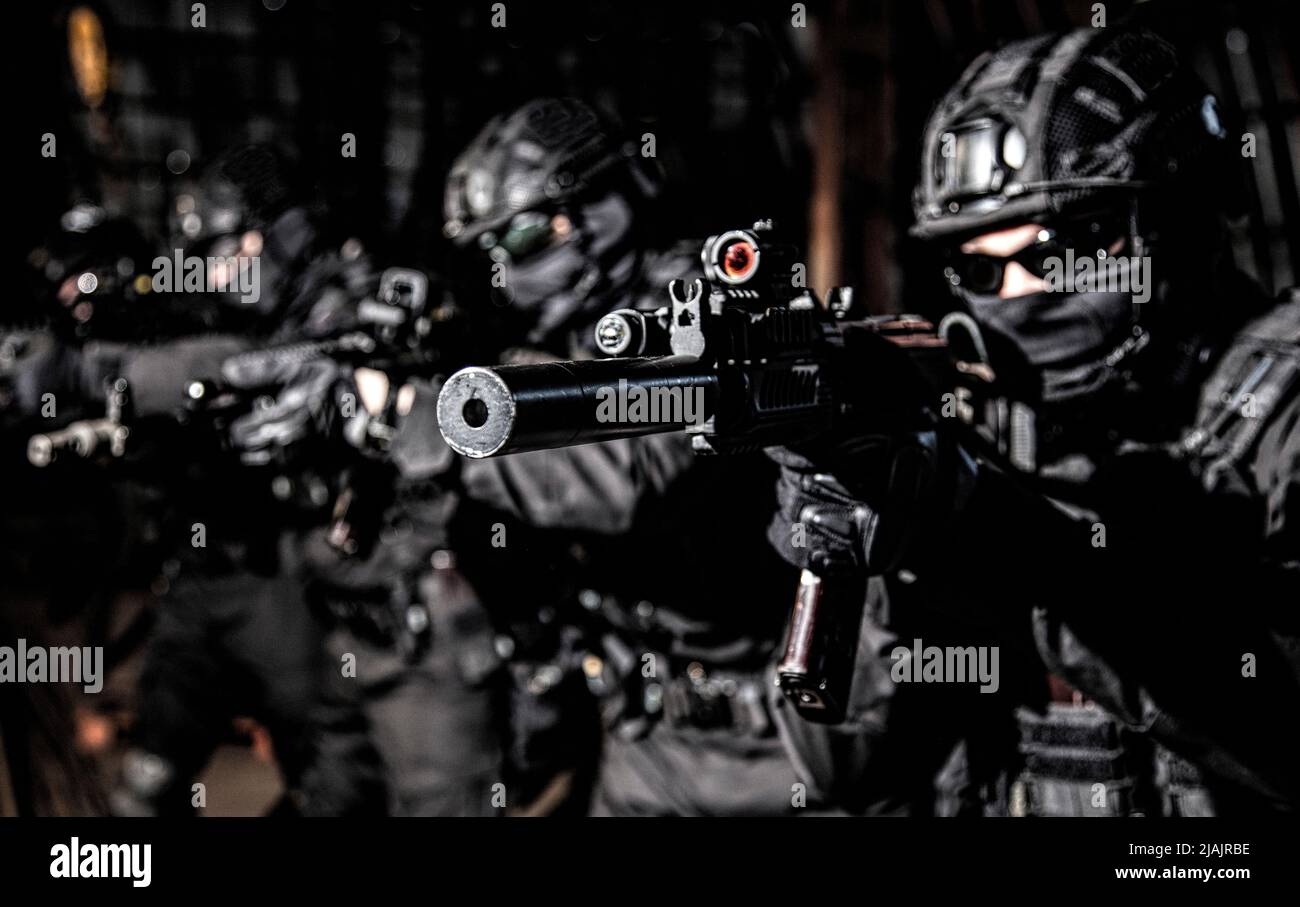 Das Polizei-SWAT-Team steht in der Schlange und zielt auf ihre Sturmgewehre. Stockfoto